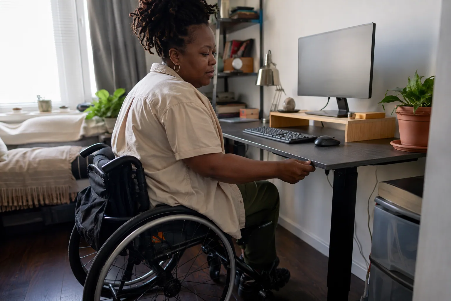 Person tidying a compact apartment home-office desk in warm afternoon light